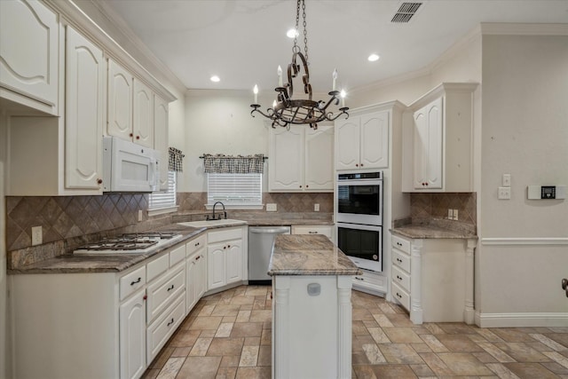 kitchen featuring white appliances, visible vents, a kitchen island, a sink, and stone finish flooring