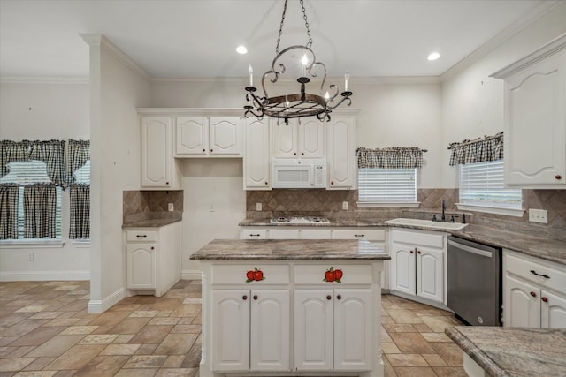 kitchen with white microwave, a chandelier, ornamental molding, stainless steel dishwasher, and a sink