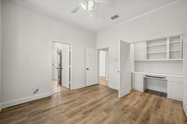 unfurnished bedroom with light wood-type flooring, visible vents, crown molding, baseboards, and built in study area