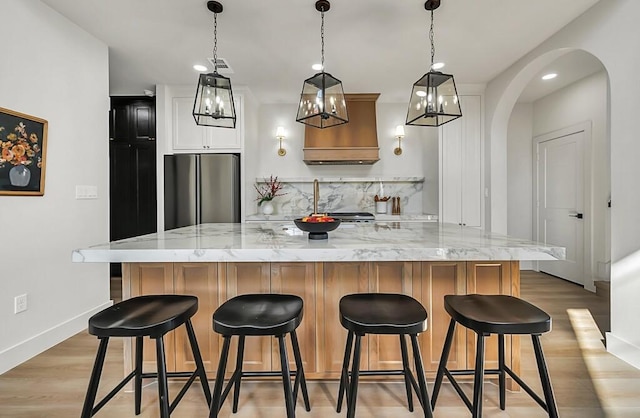 707 S 9th St, Waco, TX 76706 - kitchen featuring light stone counters, decorative backsplash, freestanding refrigerator, light wood-style floors, and arched walkways