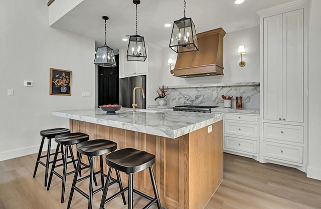 707 S 9th St, Waco, TX 76706 - kitchen featuring backsplash, custom exhaust hood, light wood-style flooring, and freestanding refrigerator