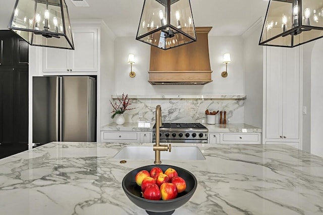 707 S 9th St, Waco, TX 76706 - kitchen with crown molding, custom exhaust hood, freestanding refrigerator, an inviting chandelier, and stove