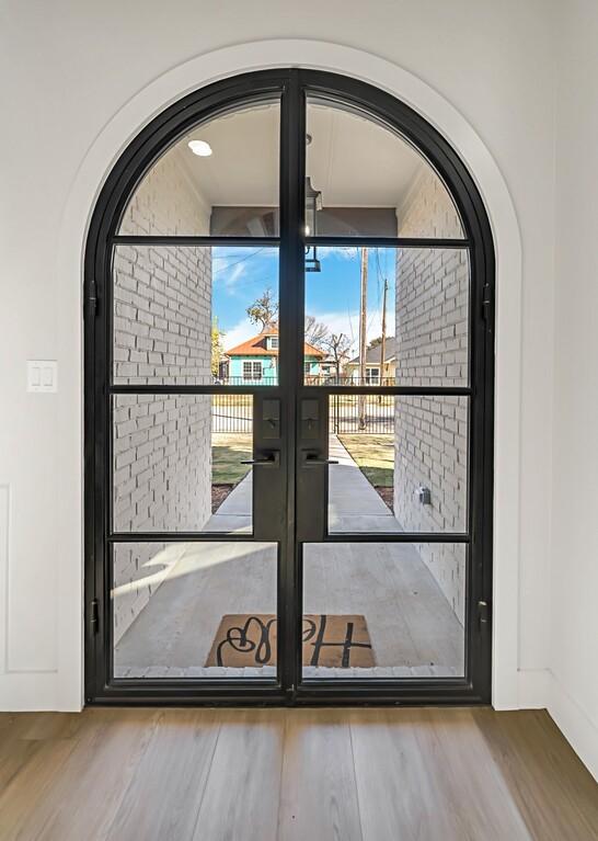 707 S 9th St, Waco, TX 76706 - doorway featuring wood finished floors, arched walkways, french doors, and baseboards