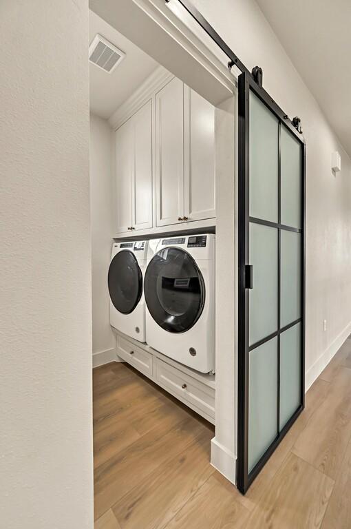 707 S 9th St, Waco, TX 76706 - laundry room with visible vents, baseboards, light wood-style flooring, cabinet space, and washing machine and dryer