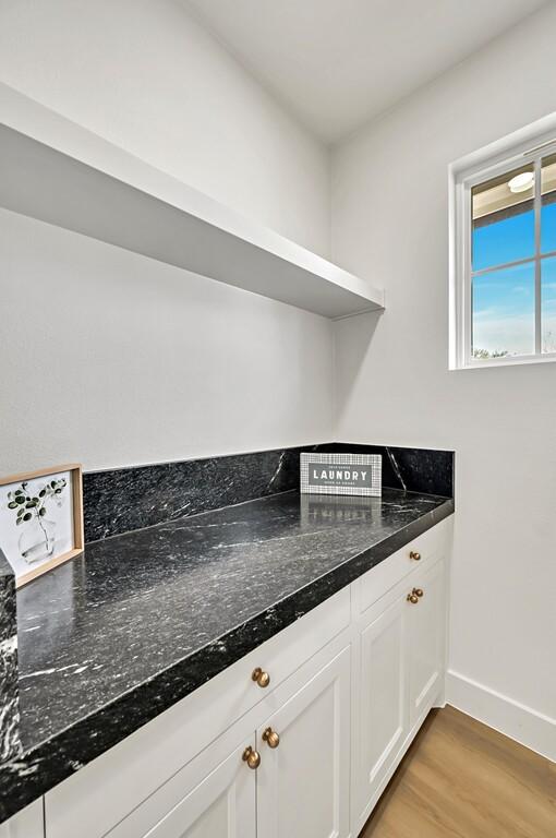 707 S 9th St, Waco, TX 76706 - kitchen featuring dark stone countertops, baseboards, open shelves, white cabinets, and light wood-style floors