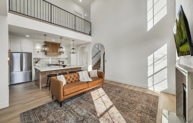 707 S 9th St, Waco, TX 76706 - living area featuring stairway, baseboards, arched walkways, a towering ceiling, and light wood-type flooring