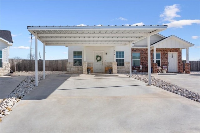 view of front facade with fence, driveway, stone siding, and a carport