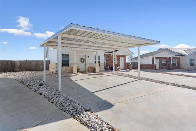 view of patio / terrace with a carport, fence, and concrete driveway