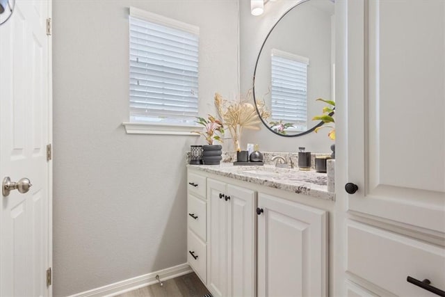 bathroom with baseboards, wood finished floors, and vanity