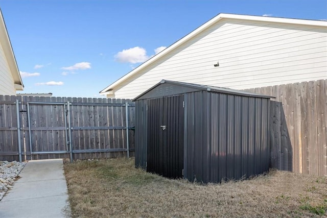 view of side of home featuring a fenced backyard, an outbuilding, and a storage shed