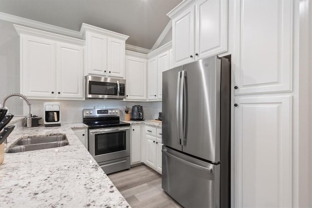 kitchen with white cabinets, stainless steel appliances, a sink, and light wood-style floors