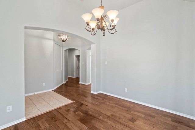 8664 Glenburne Dr, Fort Worth, TX 76131 - spare room featuring a towering ceiling, arched walkways, wood finished floors, baseboards, and an inviting chandelier