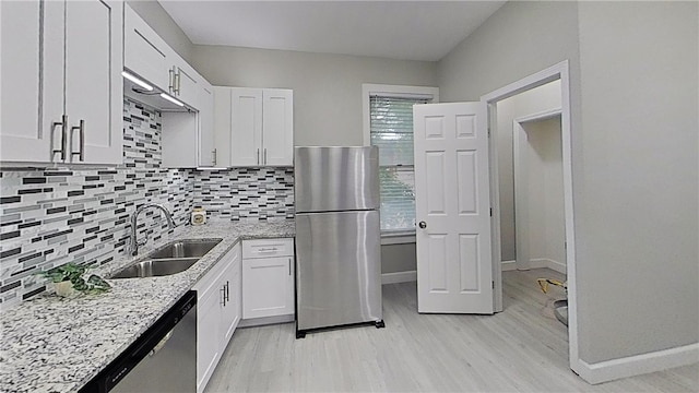 kitchen with a sink, light wood finished floors, stainless steel appliances, and white cabinetry