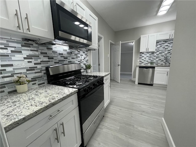 kitchen with white cabinets, appliances with stainless steel finishes, light stone counters, baseboards, and decorative backsplash