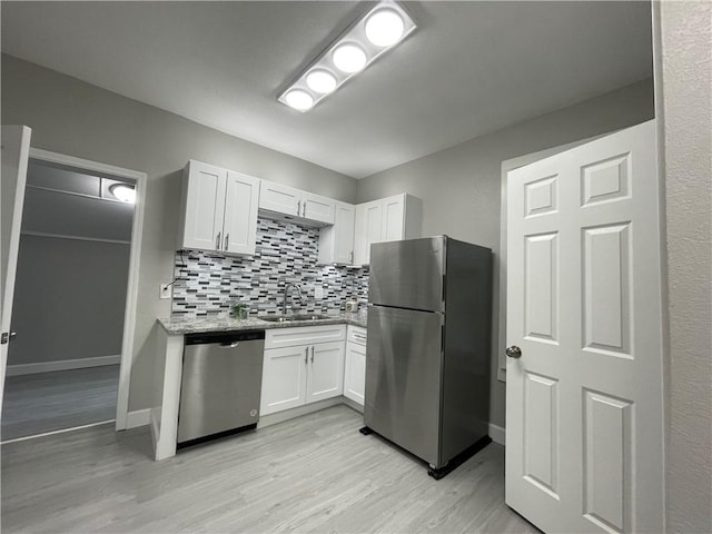 kitchen featuring a sink, light wood finished floors, stainless steel appliances, and backsplash