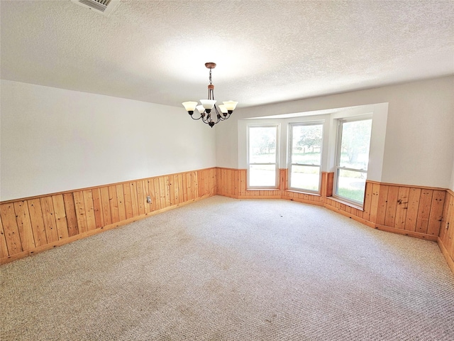 338 Lcr 866, Donie, TX 75838 - spare room with wainscoting, wood walls, a chandelier, a textured ceiling, and light colored carpet