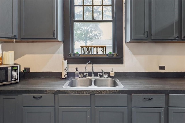 506 E Frederick St, Riesel, TX 76682 - kitchen featuring stainless steel microwave, gray cabinetry, dark countertops, and a sink