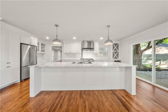 2901 Woodland Dr, Waco, TX 76710 - kitchen featuring a healthy amount of sunlight, high end fridge, white cabinets, and wall chimney range hood