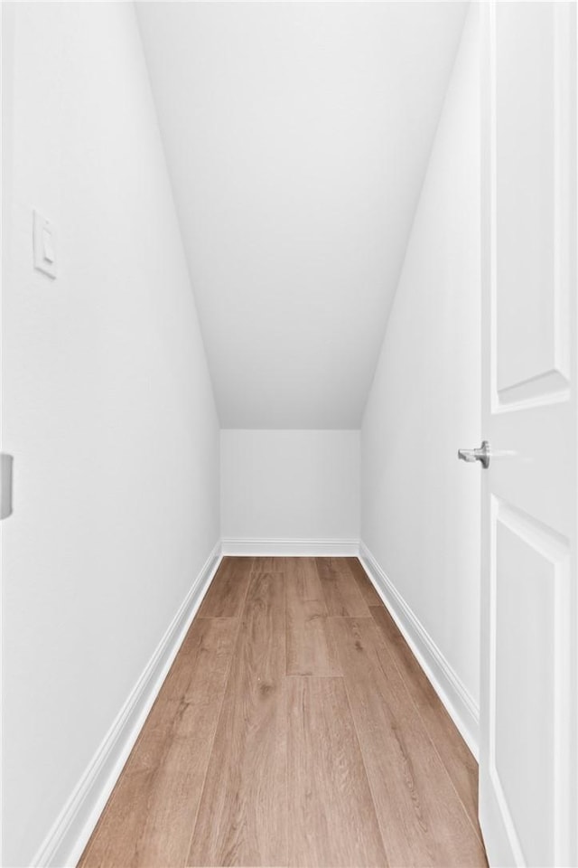 bonus room with baseboards, lofted ceiling, and wood finished floors