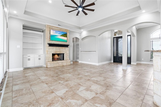 3243 N Lone Star Pkwy, Mcgregor, TX 76657 - unfurnished living room featuring a ceiling fan, arched walkways, a stone fireplace, crown molding, and a raised ceiling