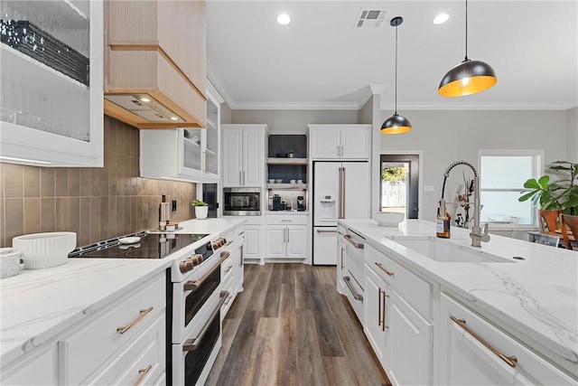 kitchen with visible vents, a sink, backsplash, high end appliances, and hanging light fixtures