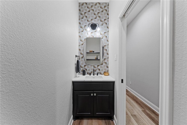 bathroom with baseboards, wood finished floors, and a textured wall