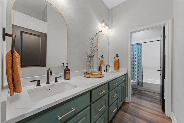 full bath featuring double vanity, toilet, wood finished floors, and a sink