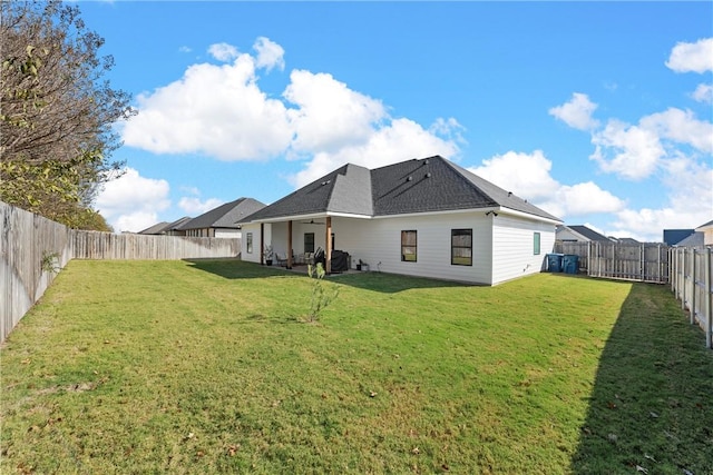 back of house with a fenced backyard and a yard