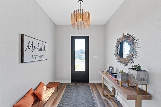 entrance foyer with baseboards, an inviting chandelier, and wood finished floors