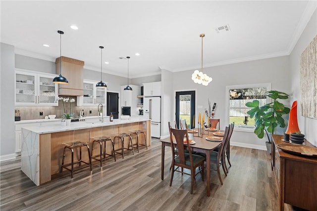 dining area with visible vents, baseboards, dark wood finished floors, and crown molding