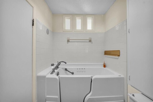 full bathroom with a tub and a textured ceiling