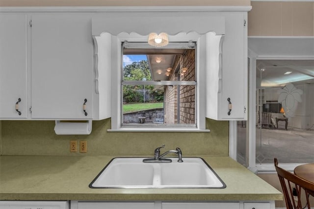 kitchen featuring light countertops, white cabinets, dishwashing machine, and a sink