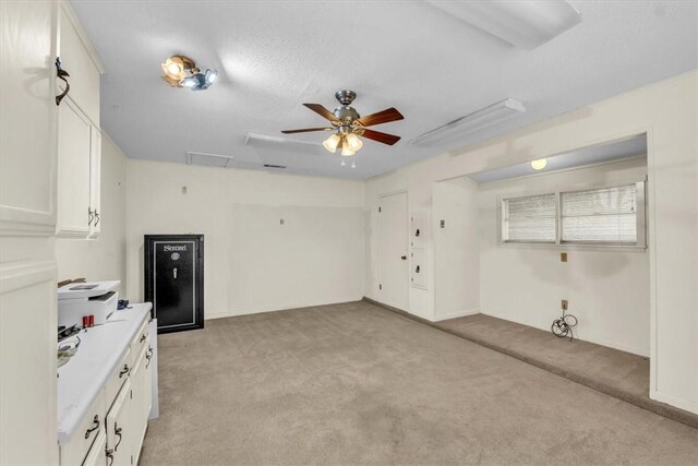interior space featuring light countertops, white cabinets, light colored carpet, and ceiling fan