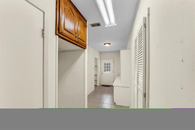 corridor featuring visible vents and light tile patterned flooring