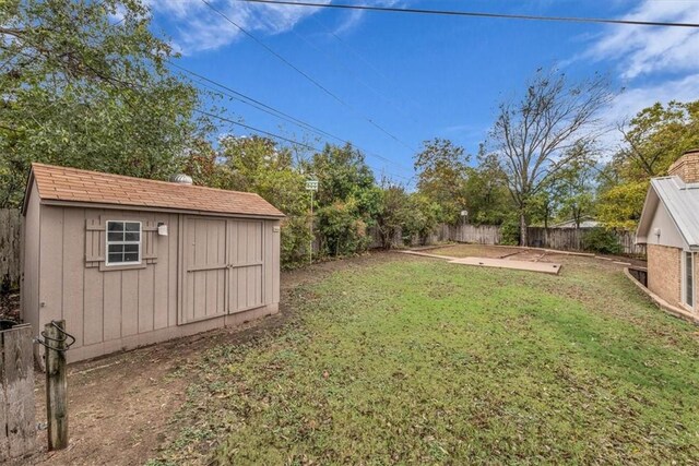 view of yard featuring a storage shed, a fenced backyard, an outdoor structure, and a patio