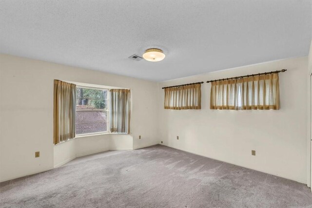 carpeted empty room with visible vents and a textured ceiling