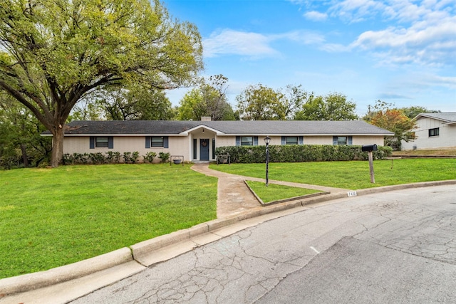 ranch-style house featuring a chimney and a front lawn