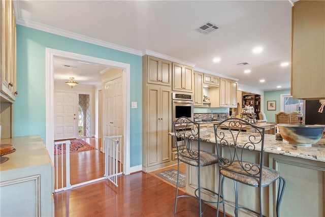 kitchen with visible vents, double oven, a kitchen breakfast bar, a peninsula, and wood finished floors