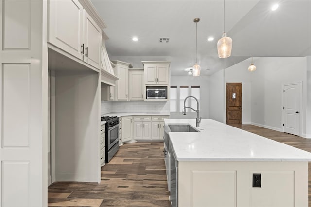 3103 Park Lake Dr, Waco, TX 76708 - kitchen featuring appliances with stainless steel finishes, a sink, dark wood finished floors, backsplash, and a center island with sink