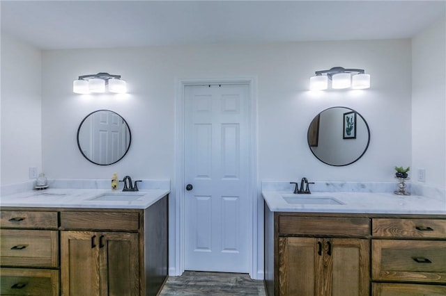 bathroom with a sink, two vanities, and wood finished floors