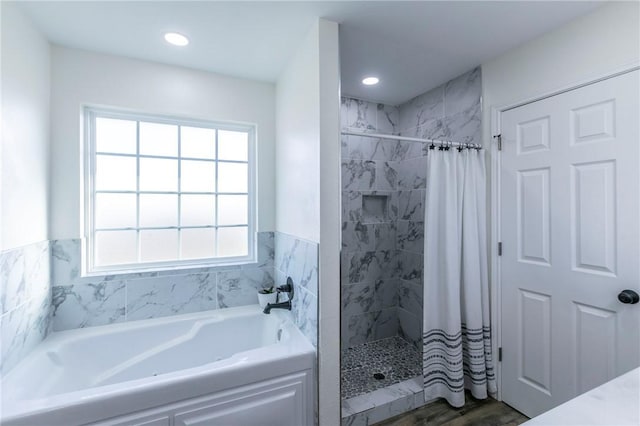 full bathroom with a wealth of natural light, a garden tub, and a tile shower
