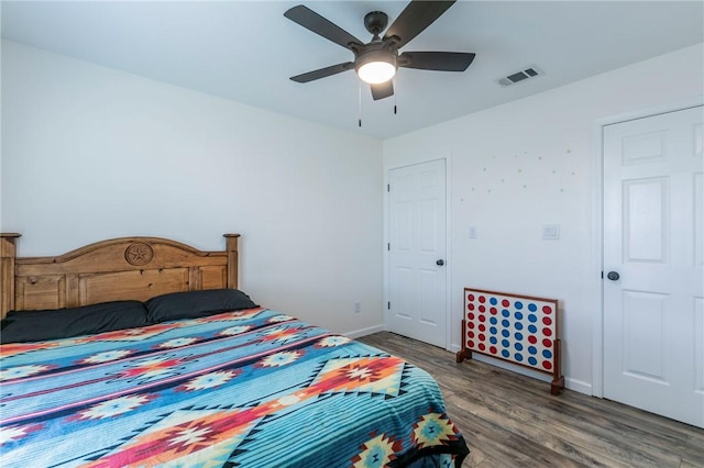 bedroom featuring visible vents, baseboards, a ceiling fan, and wood finished floors