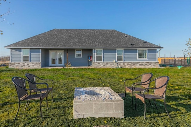 back of property with french doors, a lawn, roof with shingles, and brick siding