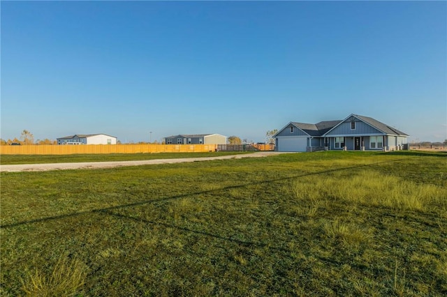 view of yard with a garage, driveway, and fence