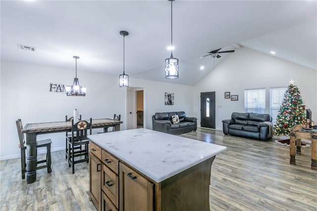 kitchen featuring visible vents, ceiling fan with notable chandelier, hanging light fixtures, and light wood finished floors