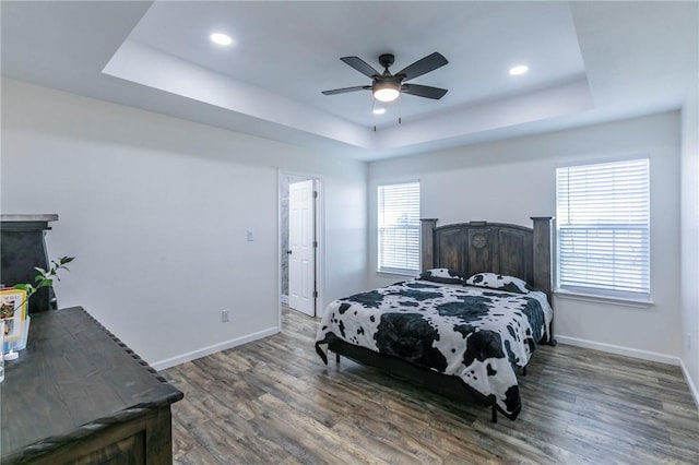 bedroom featuring a tray ceiling, wood finished floors, and baseboards