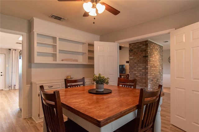 dining area with light wood-style flooring, visible vents, and ceiling fan