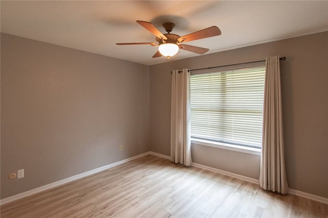 empty room with a ceiling fan, light wood-style floors, and baseboards