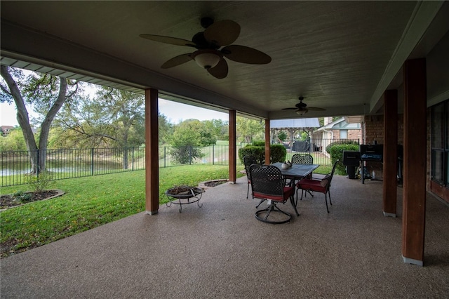 view of patio featuring outdoor dining space, a fenced backyard, a ceiling fan, and an outdoor fire pit