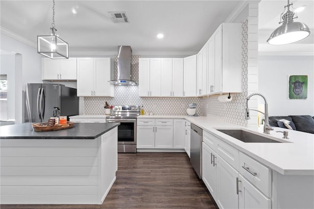 kitchen featuring visible vents, ornamental molding, a sink, stainless steel appliances, and wall chimney range hood